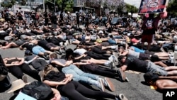 LGBTQ community members join Black Lives Matter protesters as they block an intersection laying on the street with their hands behind their backs in West Hollywood, Calif., on June 3, 2020, over the death of George Floyd. 