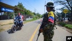 Un guerrillero de las FARC-EMC hace guardia en una carretera en un puesto de control en Corinto, Colombia, el viernes 12 de abril de 2024, el día después de que un coche bomba explotara en la cercana ciudad de Miranda.
