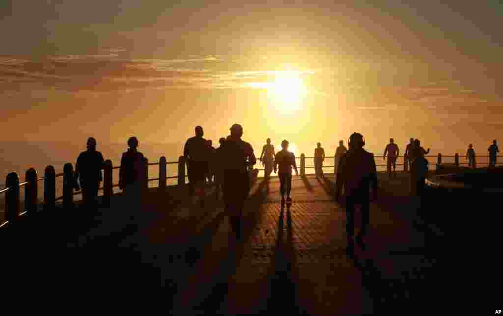 People exercise at sunrise in Sea Point, Cape Town, South Africa as the country marks day 53 of a government lockdown in a bid to prevent the spread of coronavirus.