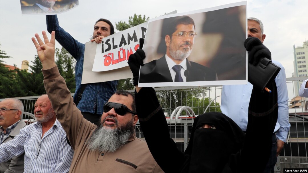 Warga membawa gambar-gambar Almarhum mantan Presiden Mesir Morsi usai shalat jenazah di Istanbul, Turki, Selasa (18/6). 