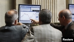 Traders look at a computer screen at the Madrid Bourse, July 24, 2012. 