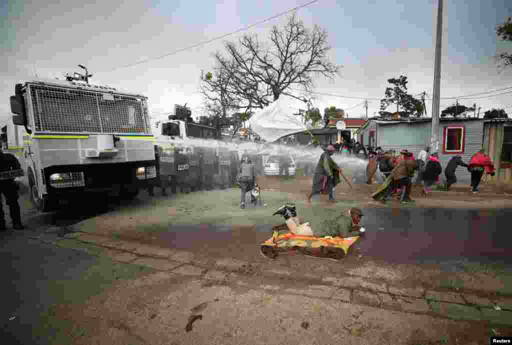 Police use a water cannon to disperse demonstrators protesting against racial and economic inequalities in Kayamandi township near Stellenbosch, South Africa.