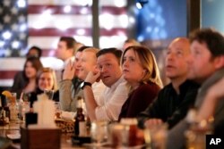 FILE - People watch as members of the House of Representatives vote on the first article of impeachment against President Donald Trump, displayed on television monitors at the Hawk 'n' Dove bar on Capitol Hill in Washington, Dec. 18, 2019.