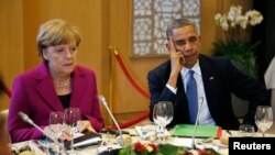 U.S. President Barack Obama and German Chancellor Angela Merkel listen during the G7 Summit working dinner in Brussels June 4, 2014. 