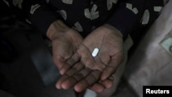 FILE - An AIDS patient in New Delhi, India, holds an anti-infectious drug.