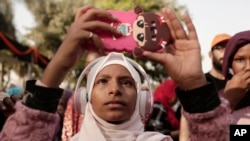FILE - A teenager films Sudanese dancers on her mobile phone during an event marking the U.N.'s International Refugee Day, in Cairo, Egypt, June 20, 2019.
