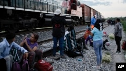 Migrantes observan un tren en marcha junto a las vías en las que esperan para subir a bordo de un vagón, con el fin de dirigirse al norte de México, el 19 de septiembre de 2023, en Huehuetoca, México. [AP]