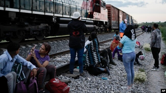 Migrantes observan un tren en marcha junto a las vías en las que esperan para subir a bordo de un vagón, con el fin de dirigirse al norte de México, el 19 de septiembre de 2023, en Huehuetoca, México. [AP]