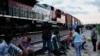 Migrantes observan pasar un tren de carga junto a las vías con la esperanza de abordarlo en Huehuetoca, México, el 19 de septiembre de 2023.