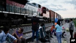 Migrantes observan pasar un tren de carga junto a las vías con la esperanza de abordarlo en Huehuetoca, México, el 19 de septiembre de 2023.