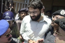 Polisi Pakistan mengawal Ahmed Omar Saeed Sheikh, yang dihukum atas kasus pembunuhan jurnalis Amerika Daniel Pearl pada 2002, saat dia keluar dari pengadilan di Karachi, Pakistan, 29 Maret 2002.