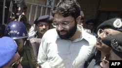 FILE - Pakistani police escort Ahmed Omar Saeed Sheikh, who was convicted in the 2002 killing of American journalist Daniel Pearl, as he exits a court in Karachi, Pakistan, March 29, 2002.