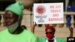 FILE - A Unemployed Graduate of South Africa holds a placard and raises her fist while staging a demonstration at Church Square in Pretoria, Aug. 14, 2020. 