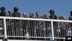 ARCHIVO - Venezolanos detenidos durante la campaña gubernamental contra opositores a los resultados de elecciones presidenciales son escoltadas por guardias nacionales a través de un puente peatonal tras ser liberados de la prisión en Tocuyito, 16 de noviembre de 2024.