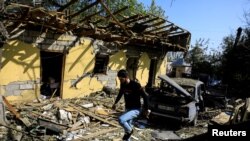 Residents search for their belongings at a restaurant hit by a shelling during the military conflict over the breakaway region of Nagorno-Karabakh, in the town of Barda, Azerbaijan, Oct. 8, 2020. 