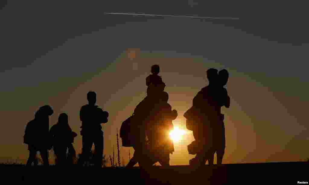 Migrants walk along rail tracks on sunset close to a migrant collection point in Roszke, Hungary.