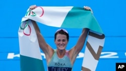 Flora Duffy of Bermuda celebrates after crossing the finish line to win the gold medal in the women's individual triathlon competition at the 2020 Summer Olympics, July 27, 2021, in Tokyo, Japan.