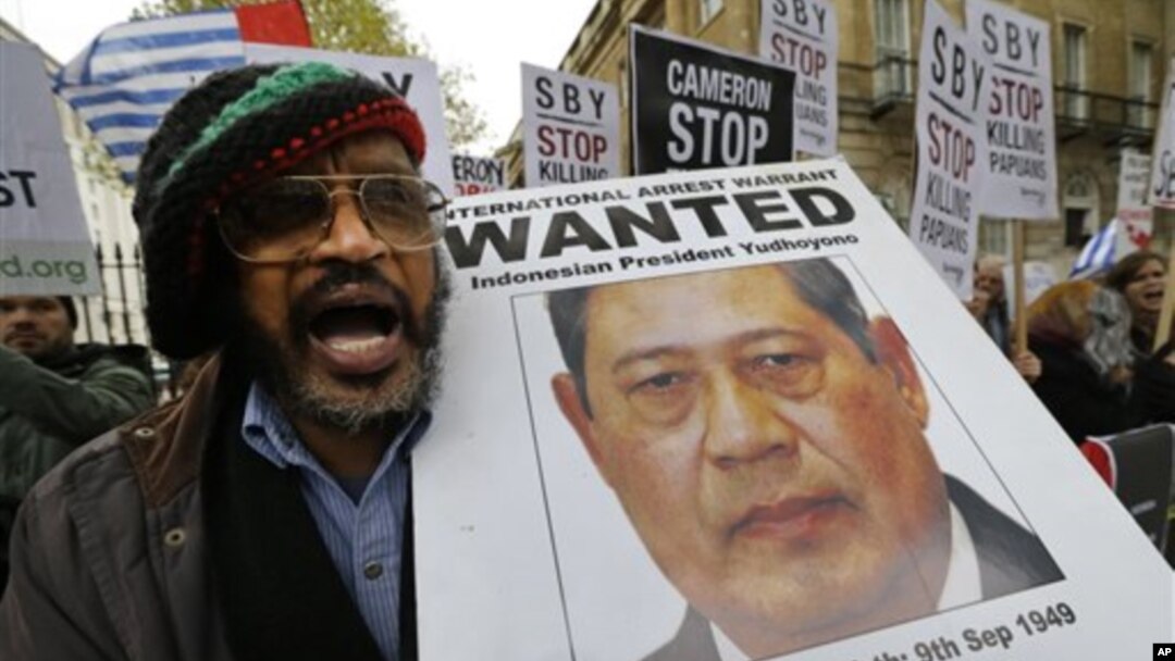 Seorang demonstran memegang gambar Presiden Susilo Bambang Yudhoyono selama unjuk rasa di depan tempat tinggal Perdana Menteri Inggris David Cameron, London. (AP/Lefteris Pitarakis)
