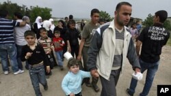 Syrian families carry their belongings as they arrive by foot in Wadi Khaled area, northern Lebanon, near the Lebanese-Syrian border, April 28, 2011