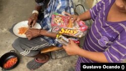 Un niño pobre venezolano conocido como "Scooby" disfruta las golosinas donadas que le lleva Freddy Paz. Foto de Gustavo Ocando, VOA.