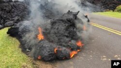 Lava del volcán Kilauea avanza sobre una calle en Leilani Estates, Pahoa, Hawái, el sábado, 5 de mayo, de 2018.