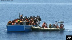 Members of an Italian Navy unit, in the boat at right, rescue migrants in the Mediterranean Sea, May 3, 2015.