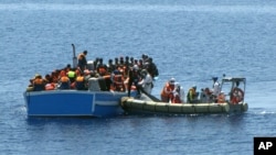 Members of an Italian Navy unit, in the boat at right, rescue migrants in the Mediterranean Sea, May 3, 2015.