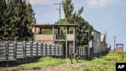 FILE —Rwandan security forces look out from their sentry box as Congolese soldiers patrol on foot on their side of the Petite Barriere border crossing with Rwanda in Goma, eastern Congo, June 17, 2022