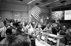 Flight controllers at the Mission Operations Control Room in the Mission Control Center at the Manned Spacecraft Center in Houston, celebrate the successful conclusion of the Apollo 11 lunar landing mission, July 24, 1969.