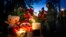 Student light candles next to flowers and portraits of victims, outside the Perm State University following a campus shooting in Perm, about 1,100 kilometers (700 miles) east of Moscow, Russia, Sept. 21, 2021. 