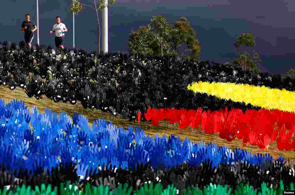 Two joggers run past the Sea of Hands exhibit on display as part of National Reconciliation Week for Aboriginal and Torres Strait Islanders, in central Sydney, Australia.