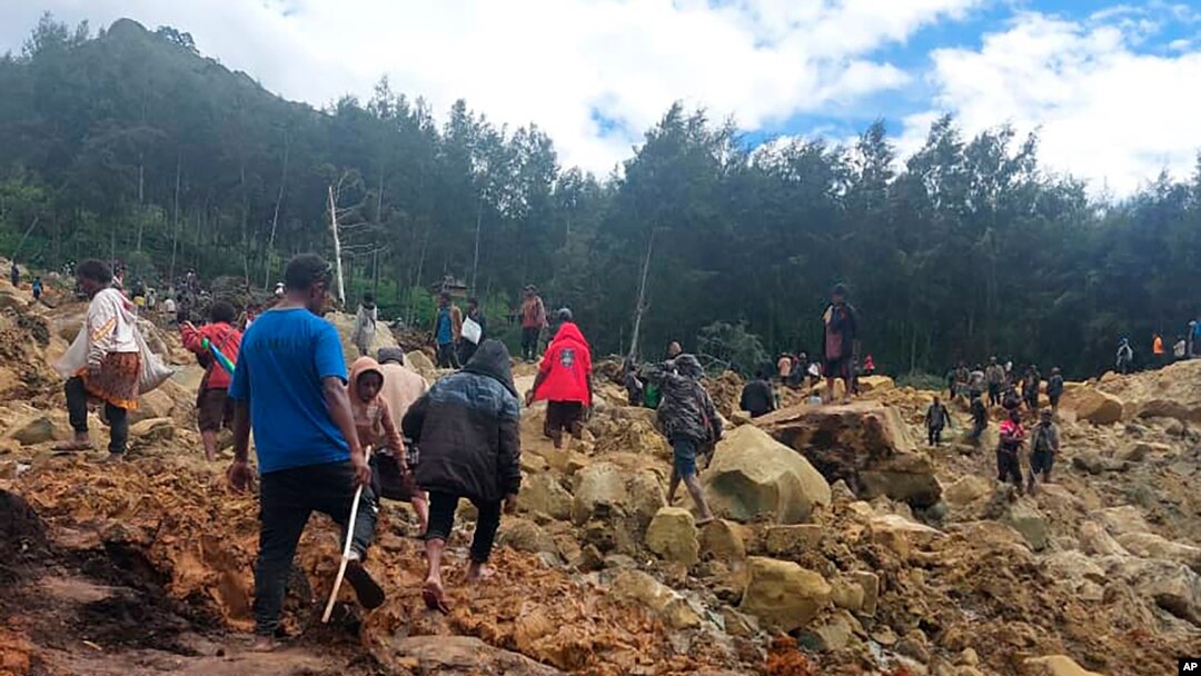 Orang-orang melintasi area longsor untuk sampai ke sisi lain di desa Yambali, Papua Nugini, Jumat, 24 Mei 2024. Lebih dari 100 orang diyakini tewas dalam bencana tanah longsor di negara kepulauan Pasifik Selatan itu. (Benjamin Sipa/Organisasi Internasional untuk Migrasi via AP)