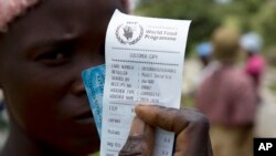 FILE —In this February 20, 2020 photo, a woman holds a voucher before receiving food aid, in Mudzi about 230 kilometers northeast of the Zimbabwean capital Harare.