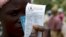 FILE —In this February 20, 2020 photo, a woman holds a voucher before receiving food aid, in Mudzi about 230 kilometers northeast of the Zimbabwean capital Harare.