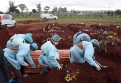 FILE - Funeral workers wearing personal protective equipment carry a casket during the burial of a COVID-19 victim at the Olifantsvlei cemetery, south-west of Johannesburg, Jan. 6, 2021.