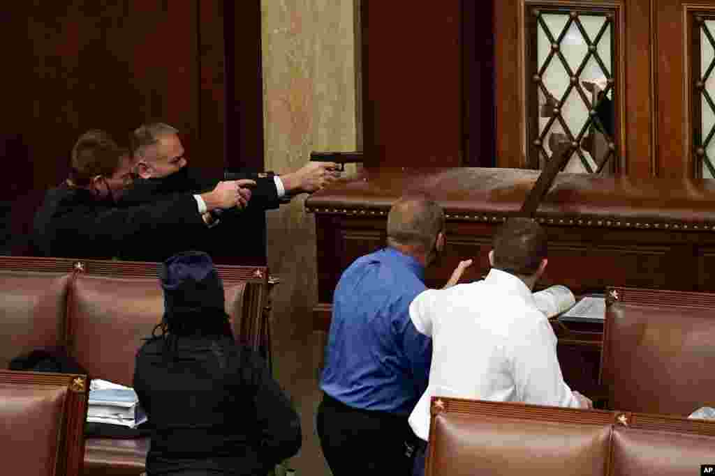 U.S. Capitol Police with guns drawn watch as protesters try to break into the House Chamber at the U.S. Capitol in Washington.