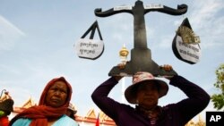 A protester from Boeung Kak lake holds a cutout of a scale symbolizing justice as she joins other villagers, who were allegedly evicted from their homes without adequate compensation, during a rally in front of the Justice Ministry in Phnom Penh, Cambodia, file photo. 