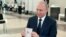 Russian President Vladimir Putin shows his passport to a member of an election commission as he arrives to take part in voting at a polling station in Moscow, Russia, July 1, 2020.