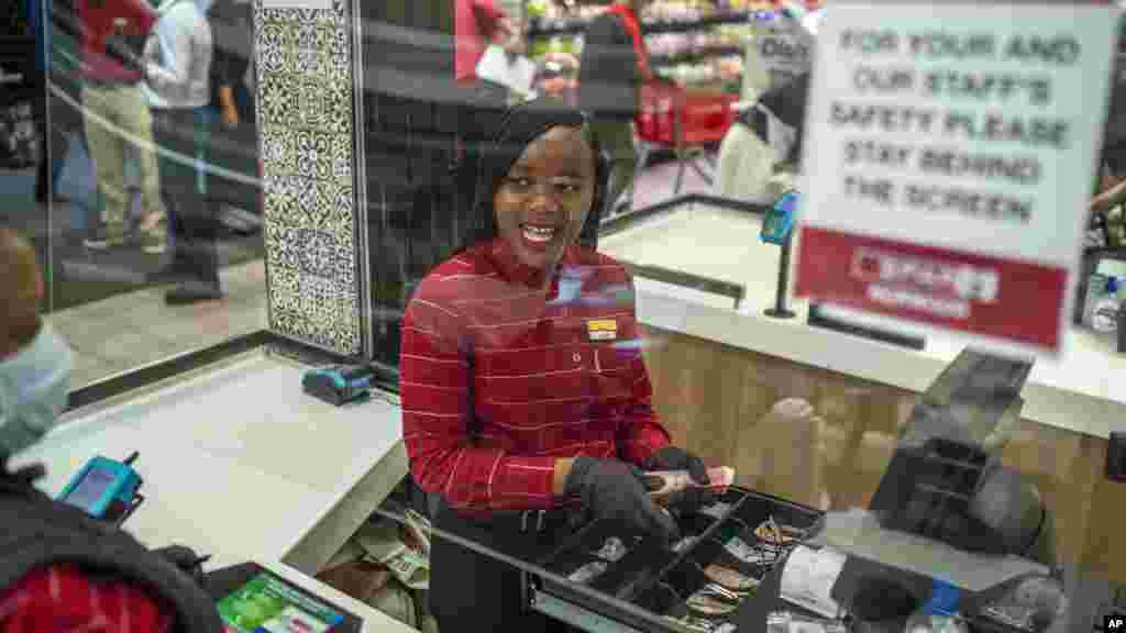 La empleada de un supermercado en un suburbio de&nbsp; Johannesburgo, Zandile Mlotshwa, de 21 años, cuenta el dinero colectado en su caja al final de su turno. Alrededor del mundo, empleados de supermercados y otros negocios esenciales permanecen en primera línea para ofrecer productos de primera necesidad como alimentos.