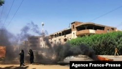 Sudanese women walk in front of tyres set ablaze by anti-coup demonstrators in the capital Khartoum, following calls for civil disobedience to protest last month's military coup, Nov. 7, 2021.