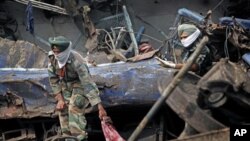 Indian army personnel pull out the body of a victim from the wreckage of a Kalka Mail passenger train that derailed near Fatehpur in Uttar Pradesh state, India, July 11, 2011