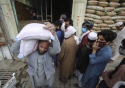 People buy sacks of flour fearing a shortage due to the coronavirus outbreak, in Peshawar, Pakistan, March 24, 2020.