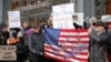 FILE - Demonstrators stand with U.S. flags and signs in a show of solidarity with the press in front of The New York Times building in New York, Feb. 26, 2017.