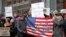 FILE - Demonstrators stand with U.S. flags and signs in a show of solidarity with the press in front of The New York Times building in New York, Feb. 26, 2017.