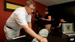FILE - Dr. Doug Owlsley, left, of the Smithsonian's National Museum of Natural History arranges the pieces from the model of the Kennewick Man for a presentation for the media at University Towers in Seattle, July 10, 2005.