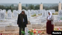 FILE - A woman reacts at a grave of her daughter, an SDF fighter killed during fightings with Islamic State militants, at a cemetery in Kobani, Syria April 4, 2019.