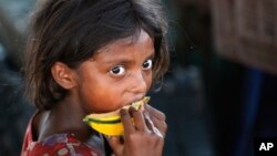 FILE - A child laborer eats a piece of a muskmelon on the World Day against Child Labor on the outskirts of Jammu, India, June 12, 2015.