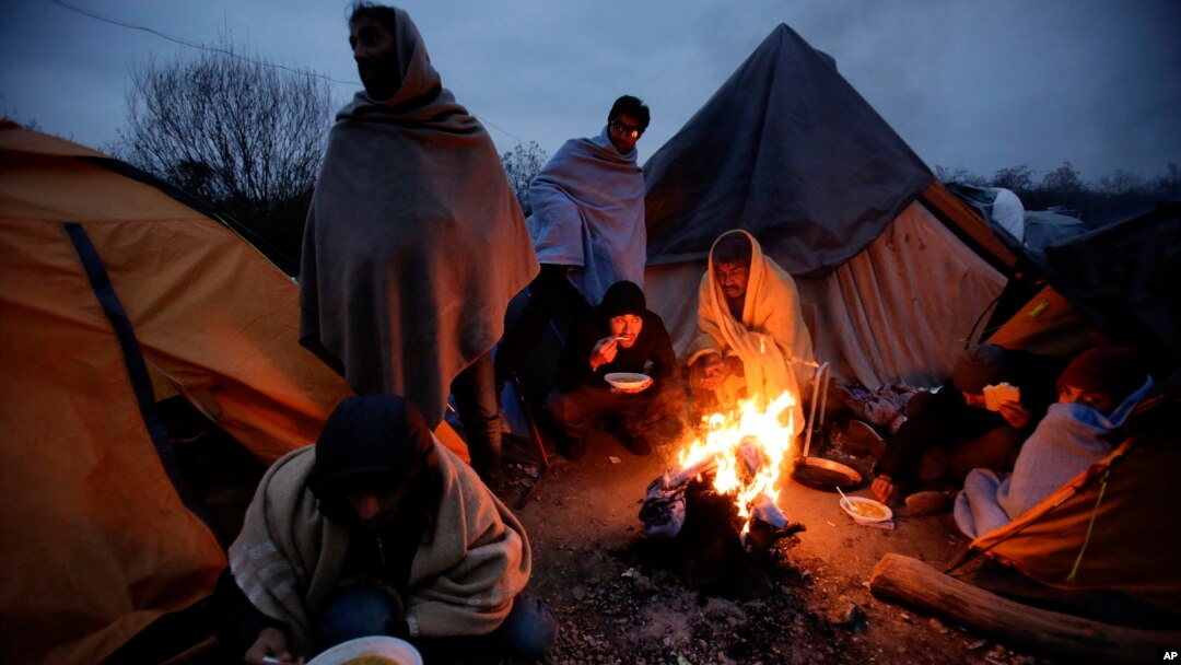 Migrants eat around a fire at a camp in Velika Kladusa, Bosnia, close to the border to Croatia, Nov. 18, 2018. 