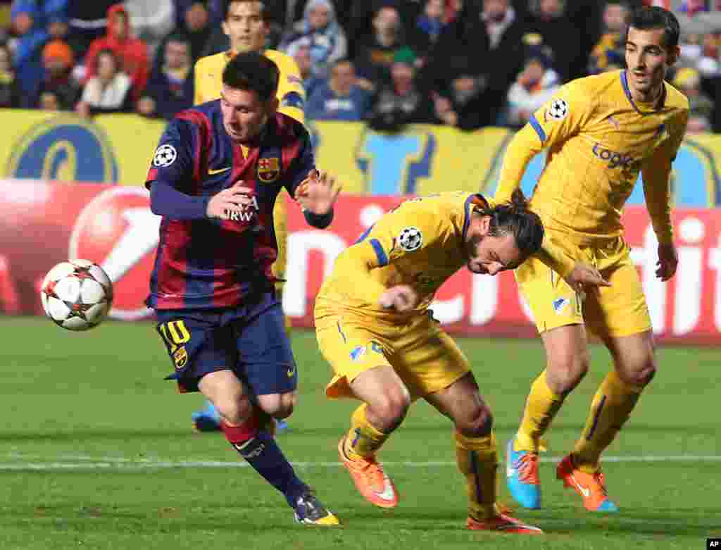 Stathis Aloneftis de l&#39;APOEL, au centre, et Marios Antoniades, à droite, en duel pour la balle avec Lionel Messi de Barcelone, à gauche, lors du match de football de la Ligue des Champions Groupe F entre Apoel et Barcelone, au stade GSP, à Nicosie, Chypre, le mardi 25 novembre , 2014. 