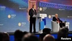 FILE - Russian President Vladimir Putin and moderator Dimitri Simes, right, attend a session of the St. Petersburg International Economic Forum in St. Petersburg, Russia, June 16, 2023. (Ramil Sitdikov/Host photo agency RIA Novosti via Reuters) 